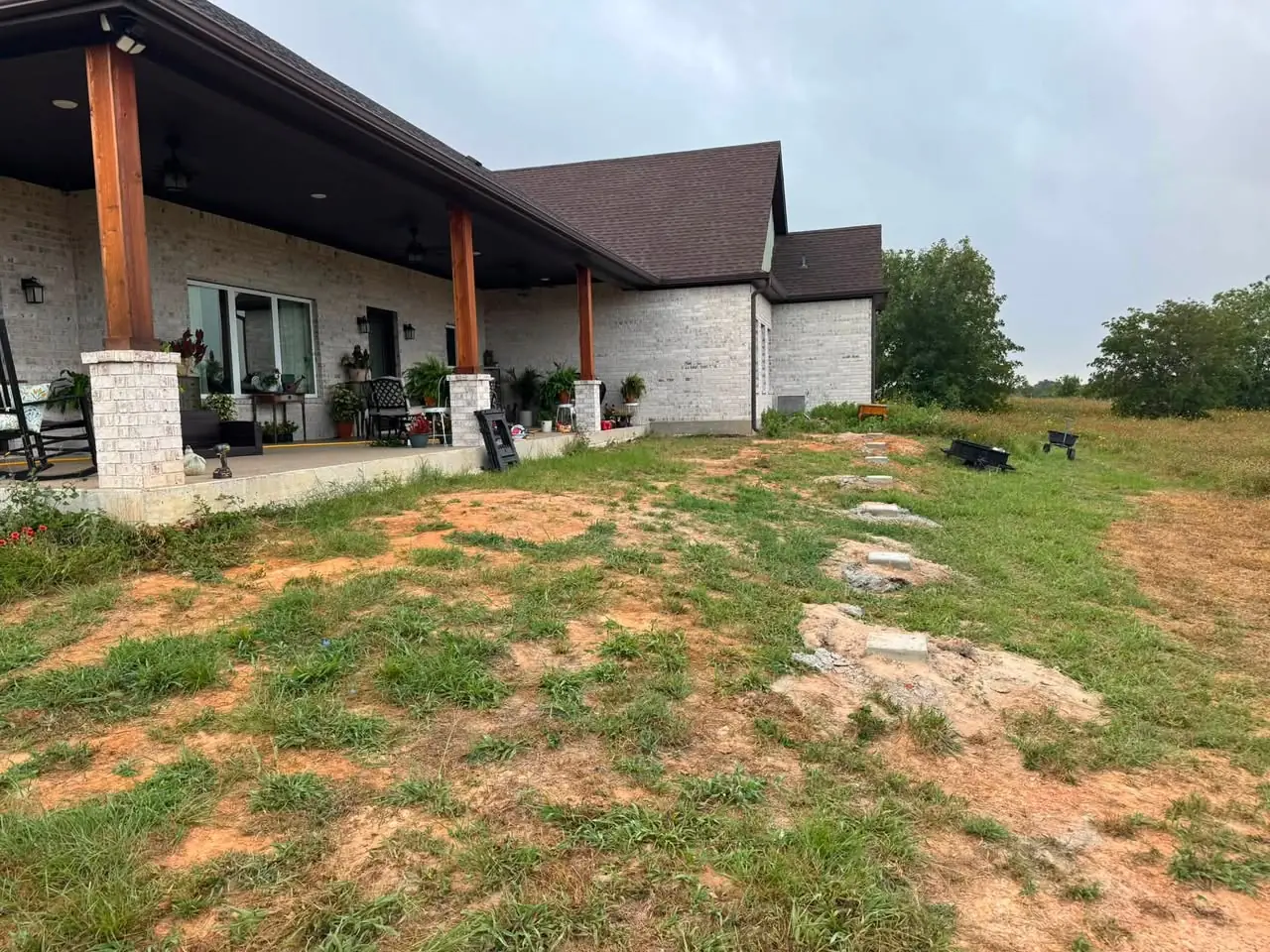Bare dirt and grass behind a brick home before the deck was built