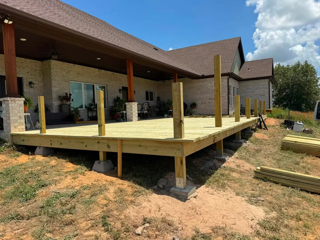 Deck framing and posts in progress behind the brick home