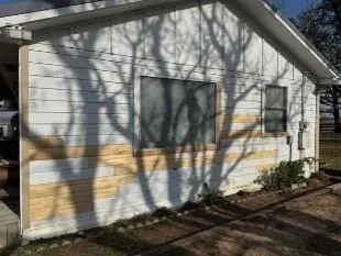 Replacement siding boards patched into a white wood-sided house